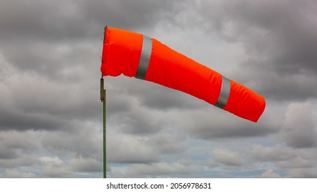 Windsock indicator of wind on tank chemical cone indicating wind direction and force. Horizontally flying windsock (wind vane) with cloud sky in the background.