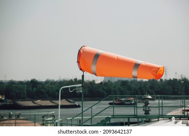 Windsock indicator of wind on tank chemical cone indicating wind direction and force. Horizontally flying windsock (wind vane) with cloud sky in the background.