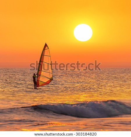 Windsurfer silhouette at sea sunset. Beautiful beach seascape. Summertime watersports activities, vacation and travel concept, vertical background.