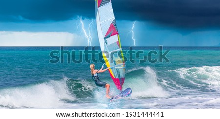 Windsurfer surfing the wind on waves, strom and lightning in the background  - Alacati, Cesme, Turkey 