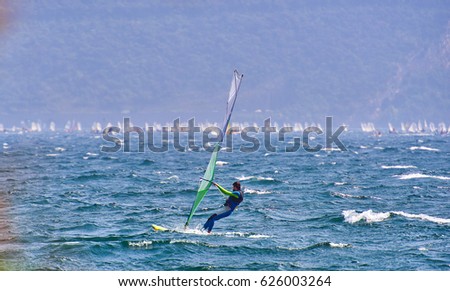 Windsurfer Surfing The Wind On Waves In Garda Lake, Recreational Water Sports, Extreme Sport Action. Recreational Sporting Activity. Healthy Active Lifestyle. Summer Fun Adventure. Hobby