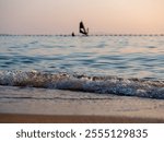 windsurfing against the background of sunset and waves