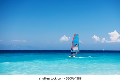 Windsurfing. Lonely surfer exercising on blue water. 