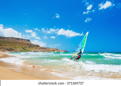 Windsurfing on the sea coast. Tropical beach with turquoise water and big waves. Crete island, Greece.