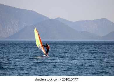 Windsurfing in the sea, water sports. View to windsurfer and green mountains in mist, scenic seascape - Powered by Shutterstock