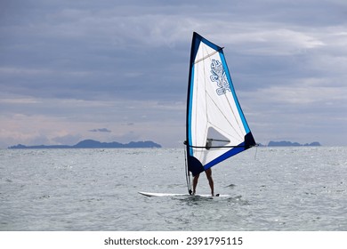 Windsurfing in the sea, water sports. View to man windsurfer and islands in mist, scenic seascape - Powered by Shutterstock