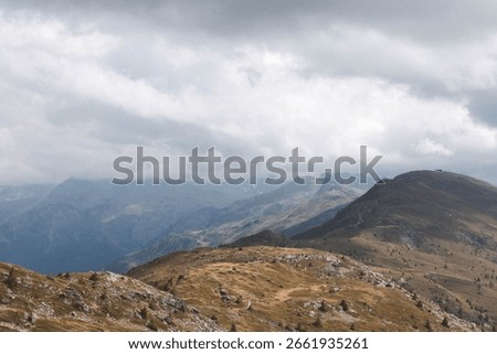 Wind-swept alpine plateau beneath brooding clouds and distant ridges
