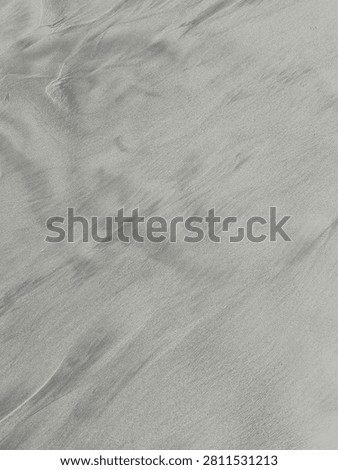 Wind-Swept Sand Patterns on the Beach. A vertical close-up highlighting subtle waves and flowing wind-swept patterns formed naturally on the surface of fine beach sand.