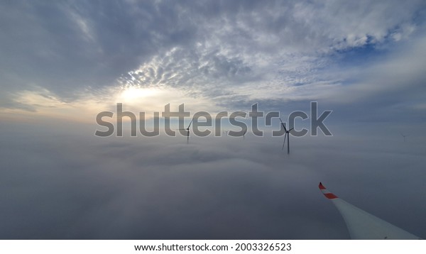 Windturbine between fog on Earth and Clouds in the\
Sky. Best Workingspace on\
Earth