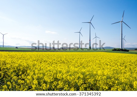 Windwheels and a yellow rapeseed field seen in Germany