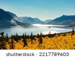 Windy Arm of Tagish Lake near Carcross, Yukon Territory YT, Canada, in autumn fall colors with wildfire still smoldering in forest of distant lake shore and mountain slope