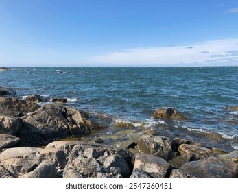 Windy day at the rocky Baltic coast of Finland. Waves crash against the rugged shoreline under a clear blue sky, capturing the natural beauty and adventurous spirit of Nordic coastal landscapes. - Powered by Shutterstock