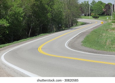 Windy Rural Road Lined With Trees And Grass.