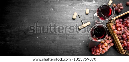 Wine background. Red wine in an old box with a corkscrew. On the black chalkboard.