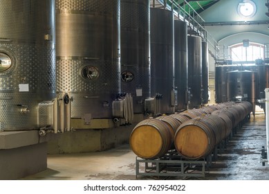 Wine barrels in the winery. Stacked oak barrels. Wine production. Stainless steel industrial silo with catwalk and faucet used in modern wine making. Chile