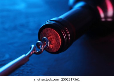 Wine bottle with corkscrew in lights on table, closeup