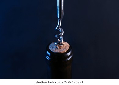 Wine bottle with corkscrew on dark background, closeup