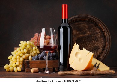 Wine bottle, grapes, cheese, glass of red wine and old wooden barrel. With copy space - Powered by Shutterstock