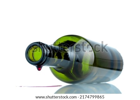 WINE BOTTLE LYING DOWN WITH LAST DROP FALLING. ALCOHOL EXCESSIVE CONSUMPTION ADDICTION. ALCOHOLISM CONCEPT. FOCUS SELECTED. WHITE BACKGROUND.