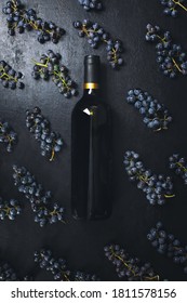 Wine in a bottle lying on a dark background decorated with bunches of grapes, top down view wine tasting concept - Shutterstock ID 1811578156