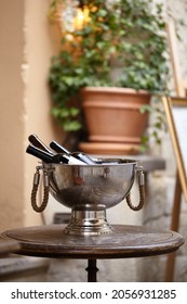 Wine bottles in a Large metal bowl standing on wooden table on the city street to attract visitors to the restaurant. Wine accessories