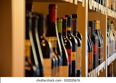 Wine Bottles On Wooden Shelf In Wine Store