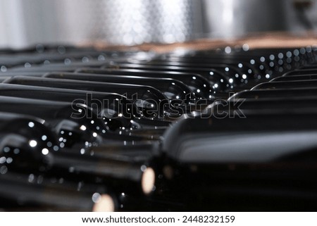 Wine bottles are stacked for storage. The bottles are in rows. New wine. A small winery. Selective focus.