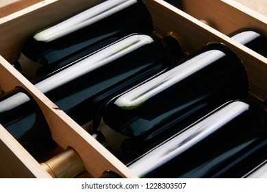 Wine Bottles In Wooden Crate On Wood Table Background, Close-up. Red Wine In Wood Box Case In Wine Shop 