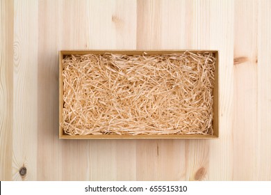 Wine box with decorative straw on wooden table, top view
