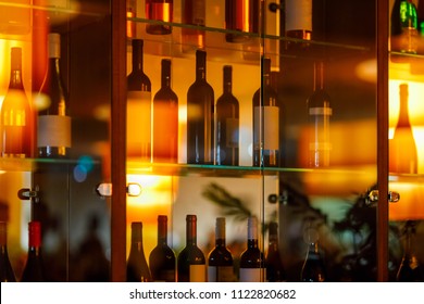 Wine cabinet with glass shelves and door and reflections. red and white wines