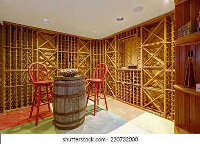 Wine Cellar Interior In Basement Room With Decorative Wooden Barrel And Two Red High Chairs