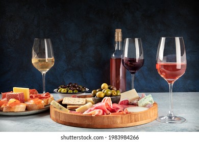 Wine and charcuterie and cheese board with a place for text. Prosciutto di parma ham, blue cheese, olives and salmon sandwiches, Italian antipasti or Spanish tapas, a side view with copy space - Shutterstock ID 1983984266