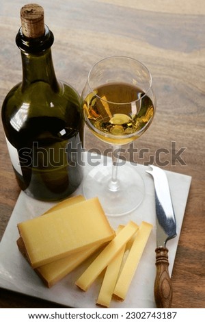 Wine and cheese pairing, local Comte cheese produced in the Franche-Comte region and glass and clavelin bottle special and characteristic yellow wine vin jaune from Jura region, France