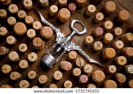 Wine corks of different sizes and a corkscrew standing upright on an old wooden surface. Background for liquor.