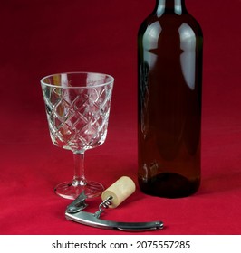 Wine Glass With Wine Bottle And Corkscrew With Cork Isolated On A Mottled Red Background