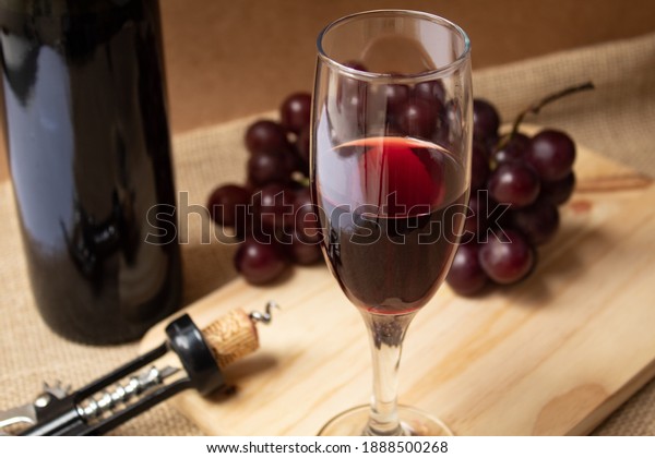 \
Wine glass with bunch of grapes and bottle\
of wine in the\
background