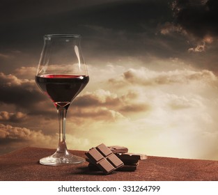 Wine glass and chocolate with orange sunset cloudscape
