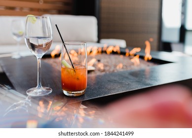 Wine glass and cocktail next to fire pit with cozy comfortable modern furniture - Prismatic reflection with glass - Inviting mood with contemporary style