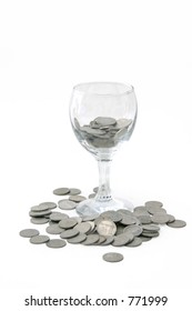 Wine Glass With Coins Poured Out Over A White Background