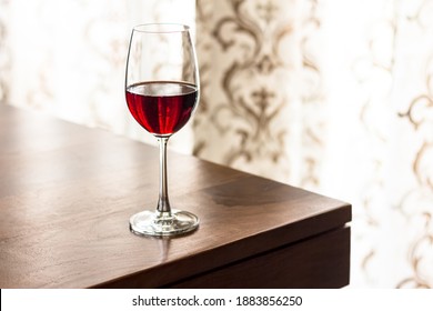 Wine Glass Filled With Red Wine On The Edge Of The Table On Bright Background