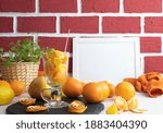 wine glass full of orange slices and a table full of fruits, behind a photo frame, against a brick wall background