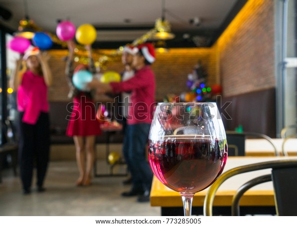 Wine glass with group of friend celebrating\
Christmas and New Year party, having fun, playing balloon in\
background. New year, xmas or alcohol drinking and safety driving,\
drink do not drive\
campaign
