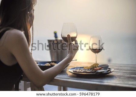 wine glass holding in woman hand with dinner set in background at shadow light of sunset