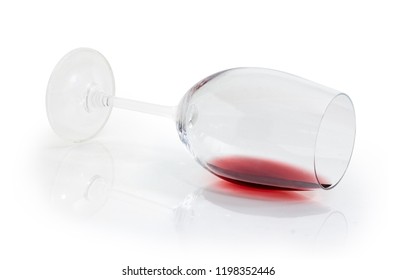 Wine Glass Lying On Its Side With Small Amount Of Red Wine On A White Background
