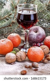 Wine Glass With Mandarin, Walnuts, Hazelnuts And Apple In Winter Decor