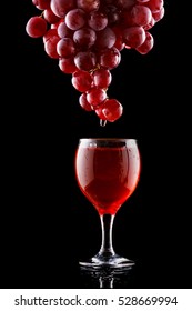 Wine glass and red grapes on a black background