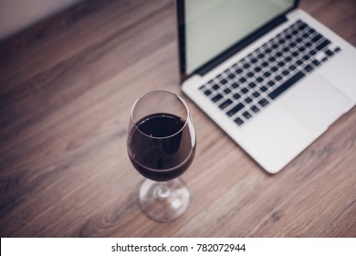 Wine glass with red wine and laptop computer - Powered by Shutterstock