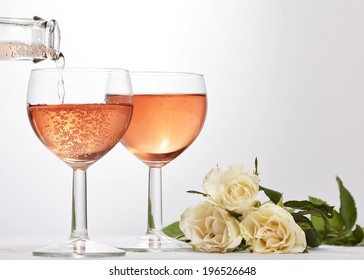 Wine Glass With Red Sparkling Drink Poured In And White Roses