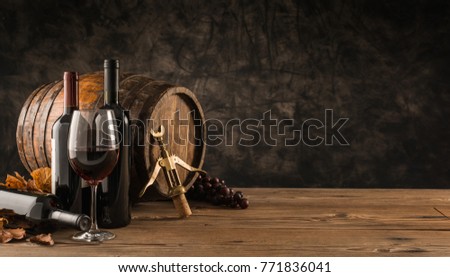 Wine glass, wooden barrel and collection of excellent red wine bottles in the cellar: traditional winemaking and wine tasting concept Сток-фото © 