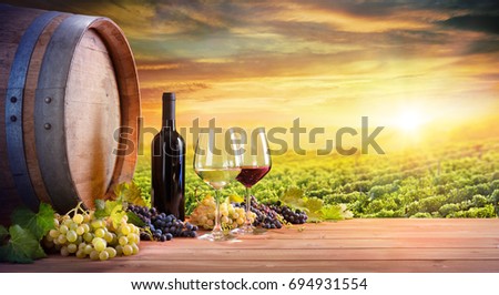 Wine Glasses And Bottle With Barrel In Vineyard At Sunset
